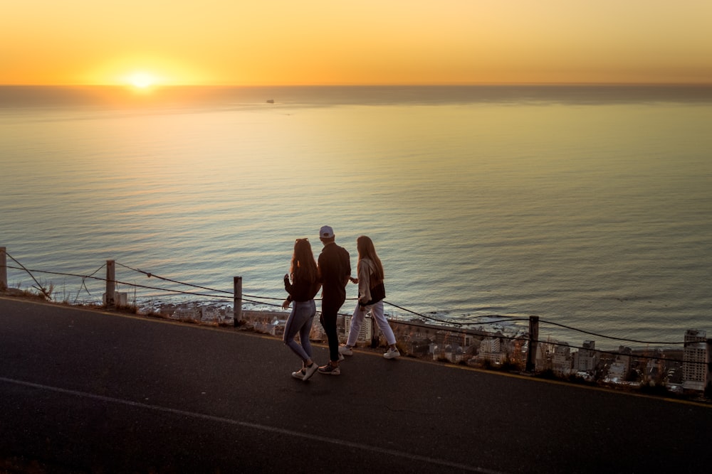 man and woman walking on the bridge during sunset