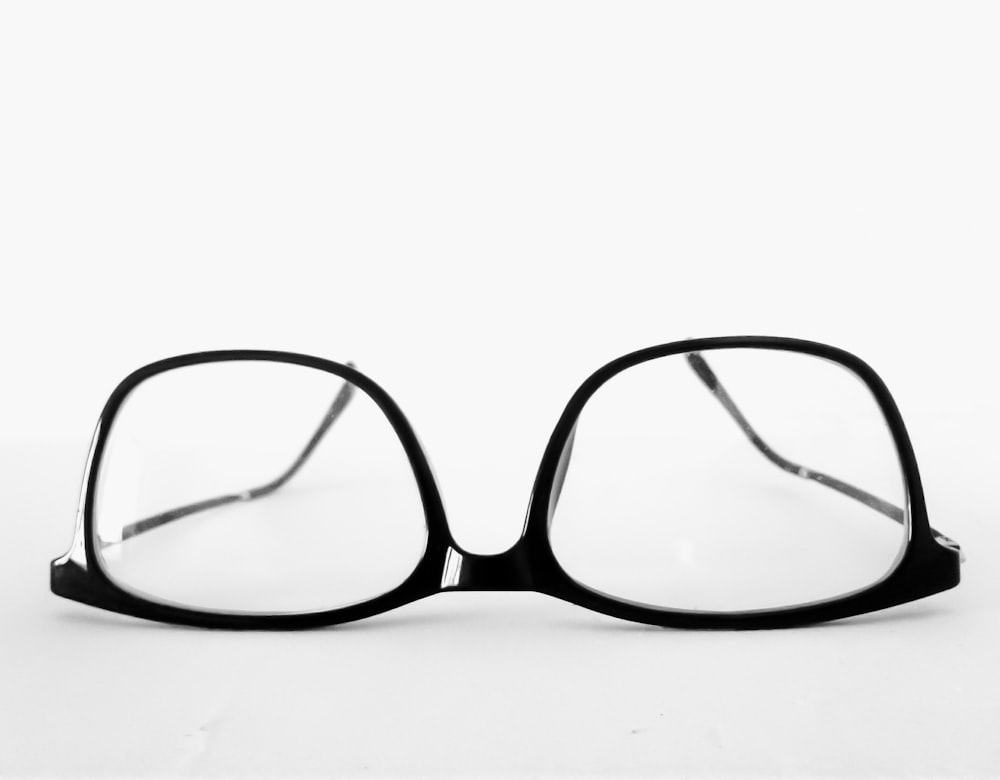 occhiali da vista con montatura nera su superficie bianca