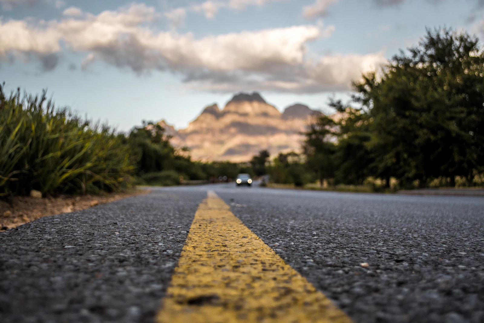 Low view along a paved South African road toward rugged mountains