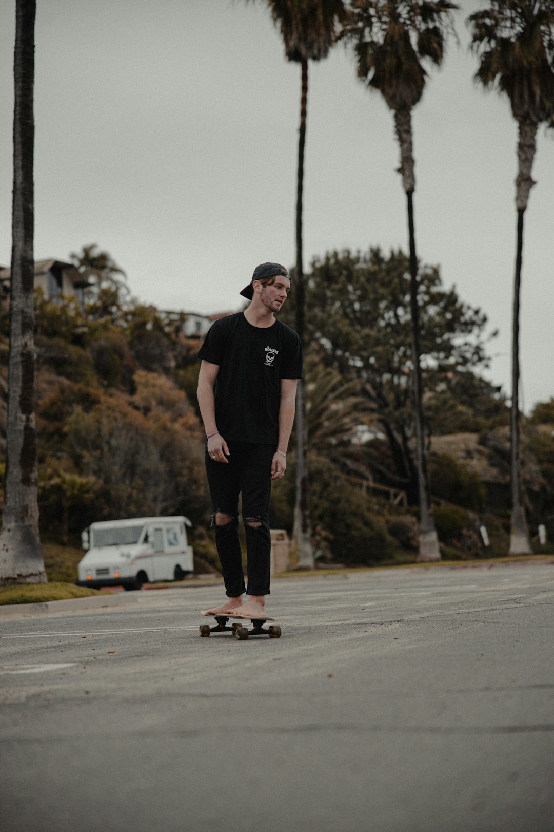 man in black t-shirt and black pants standing on road during daytime