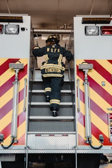 a fireman climbing the stairs of a fire truck