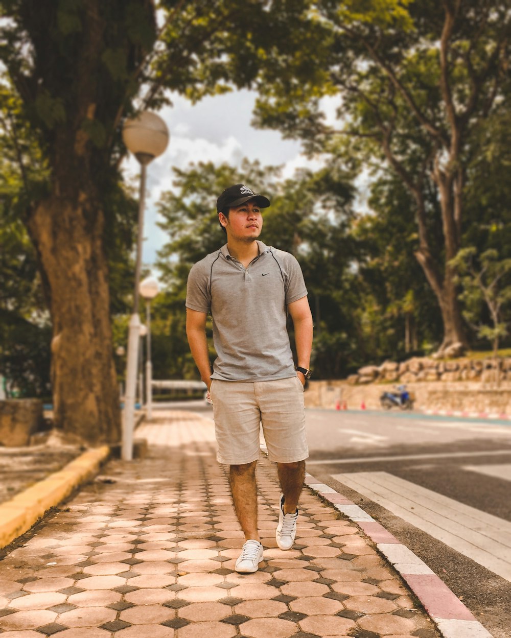 man in gray crew neck t-shirt and white shorts walking on pedestrian lane during daytime