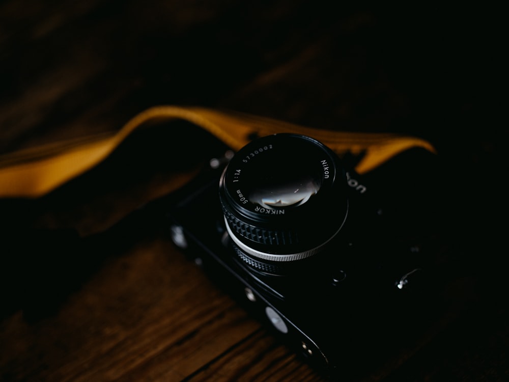 茶色の木製テーブルに黒のニコンデジタル一眼レフカメラ
