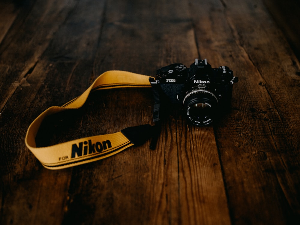 Cámara DSLR Nikon negra sobre mesa de madera marrón