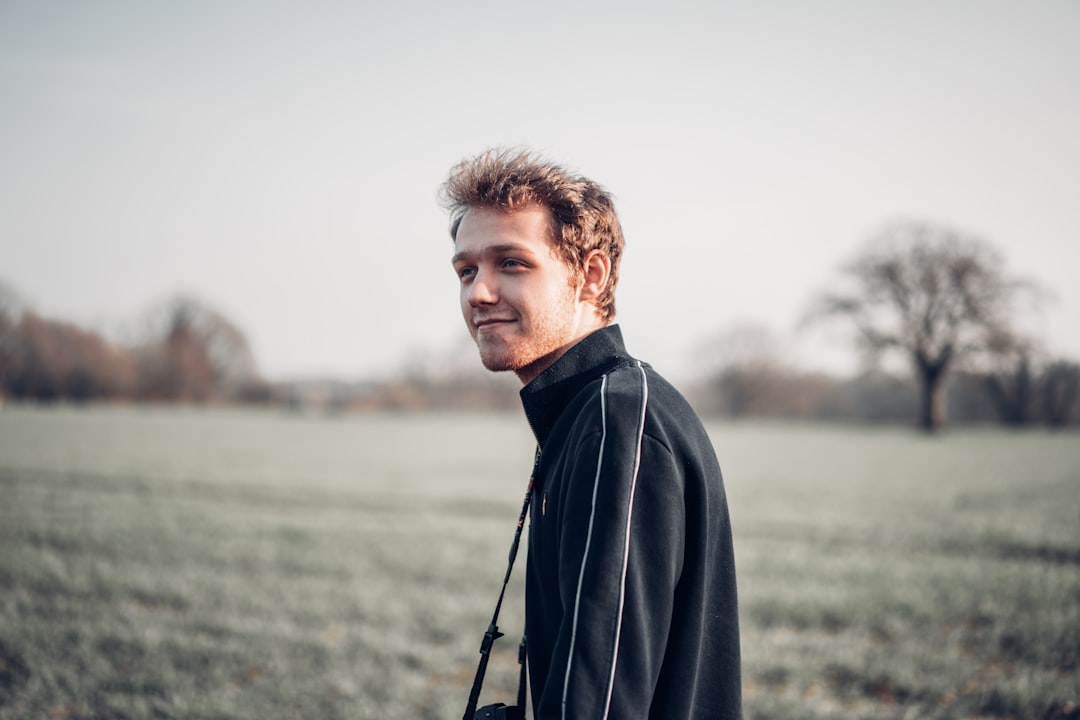 man in black jacket standing on green grass field during daytime