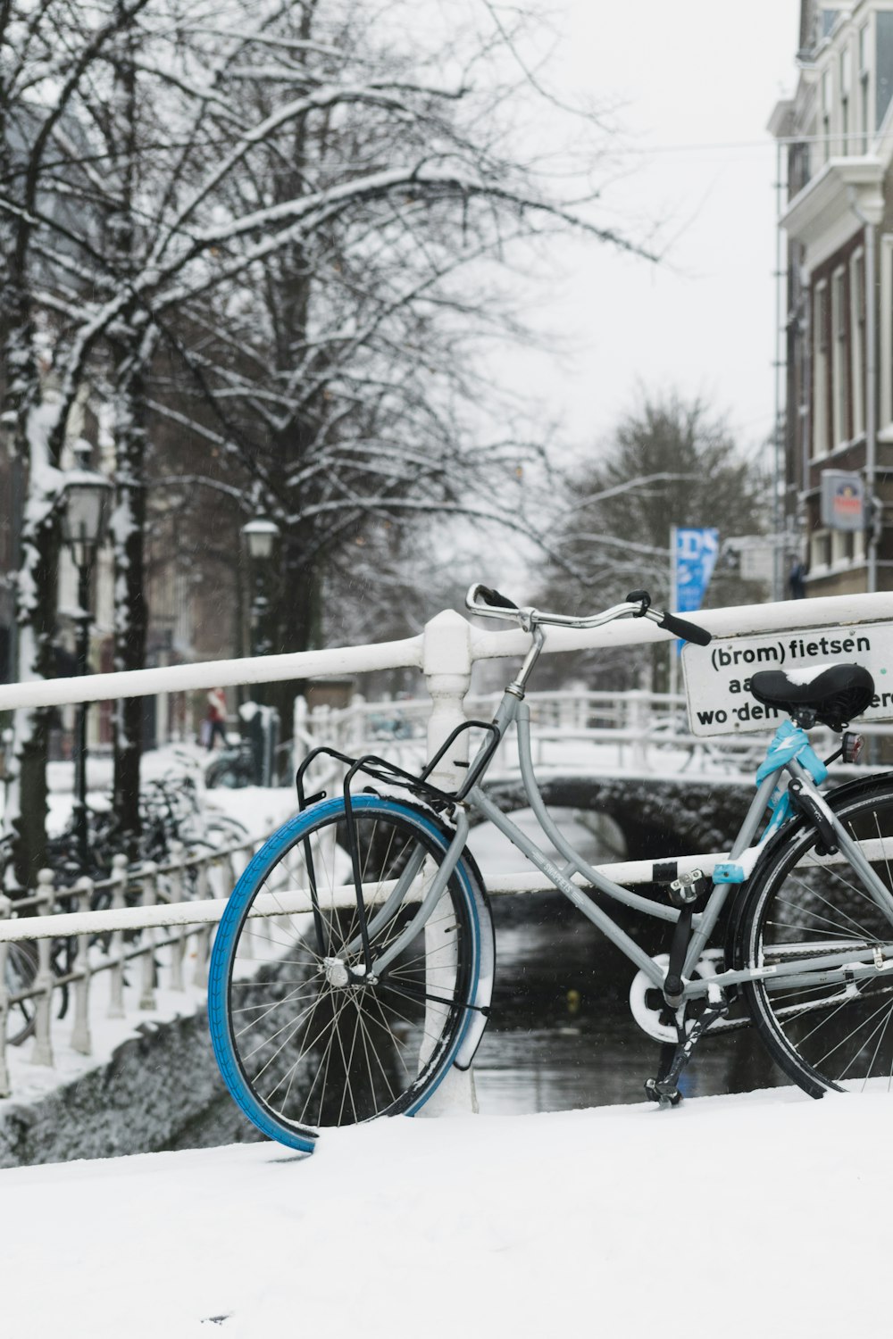 blue and black city bike on snow covered bridge during daytime