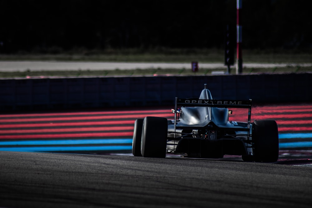 Voiture de course F 1 rouge et noire sur la piste pendant la journée