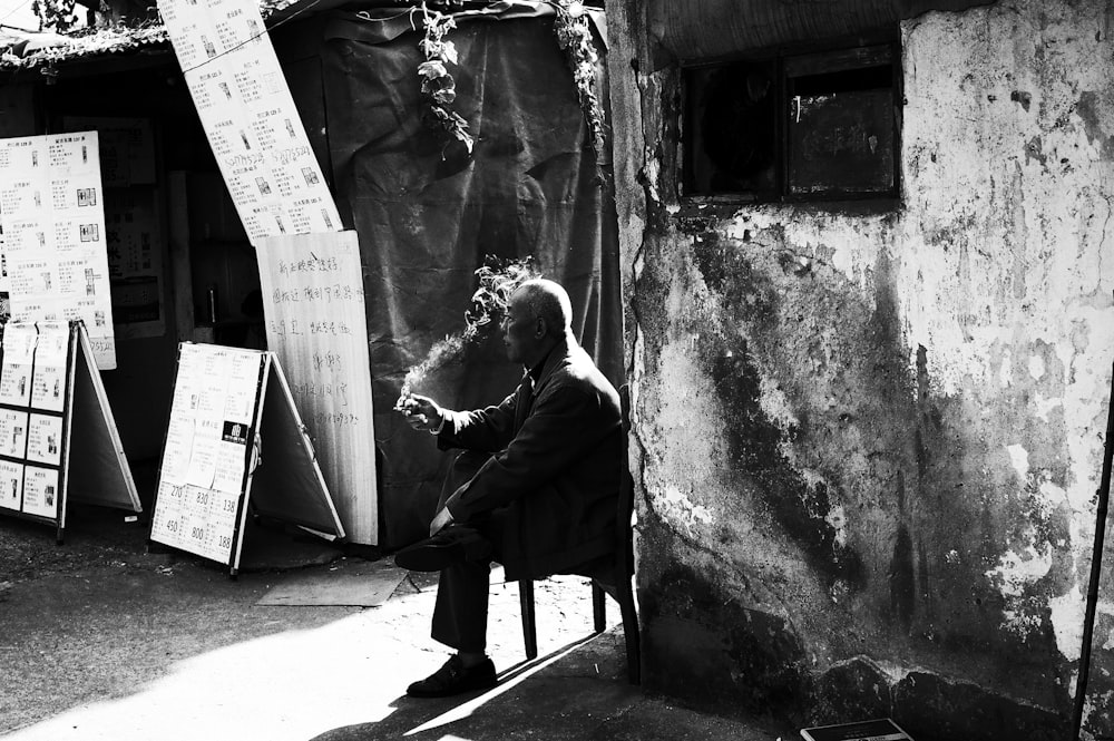 grayscale photo of woman in black coat sitting on chair