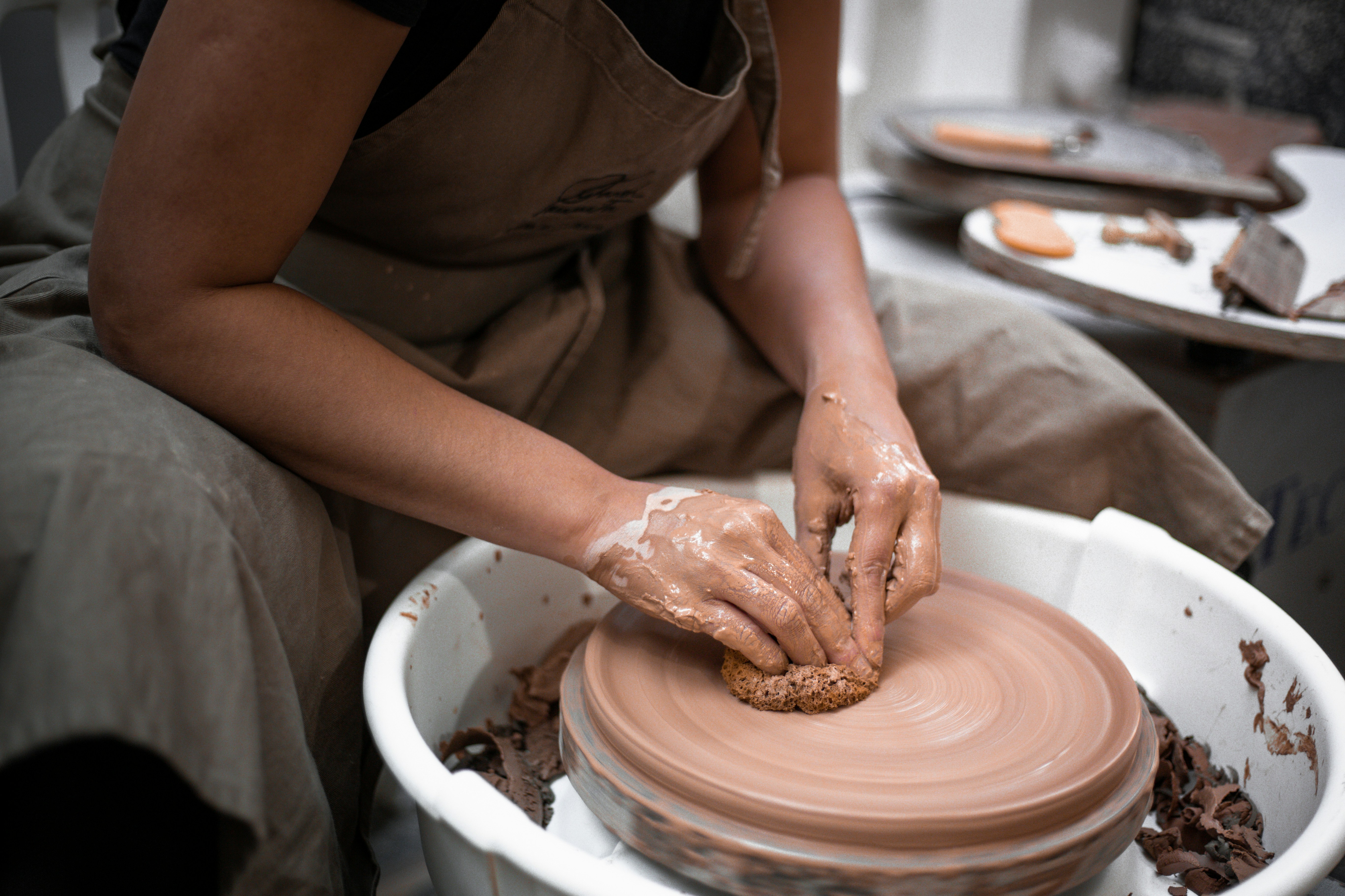person making clay pot with brown clay