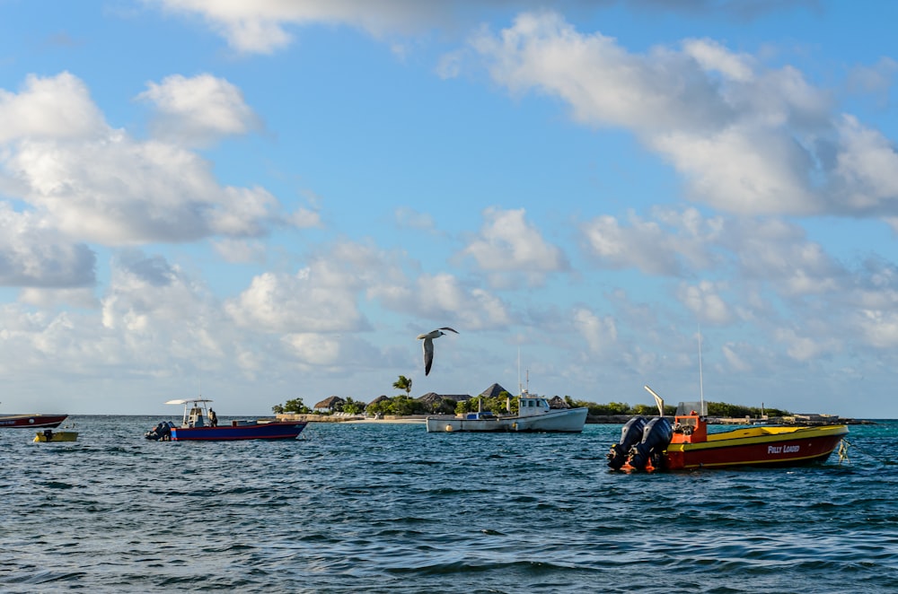 weißes und rotes Boot auf See unter blauem Himmel und weißen Wolken tagsüber