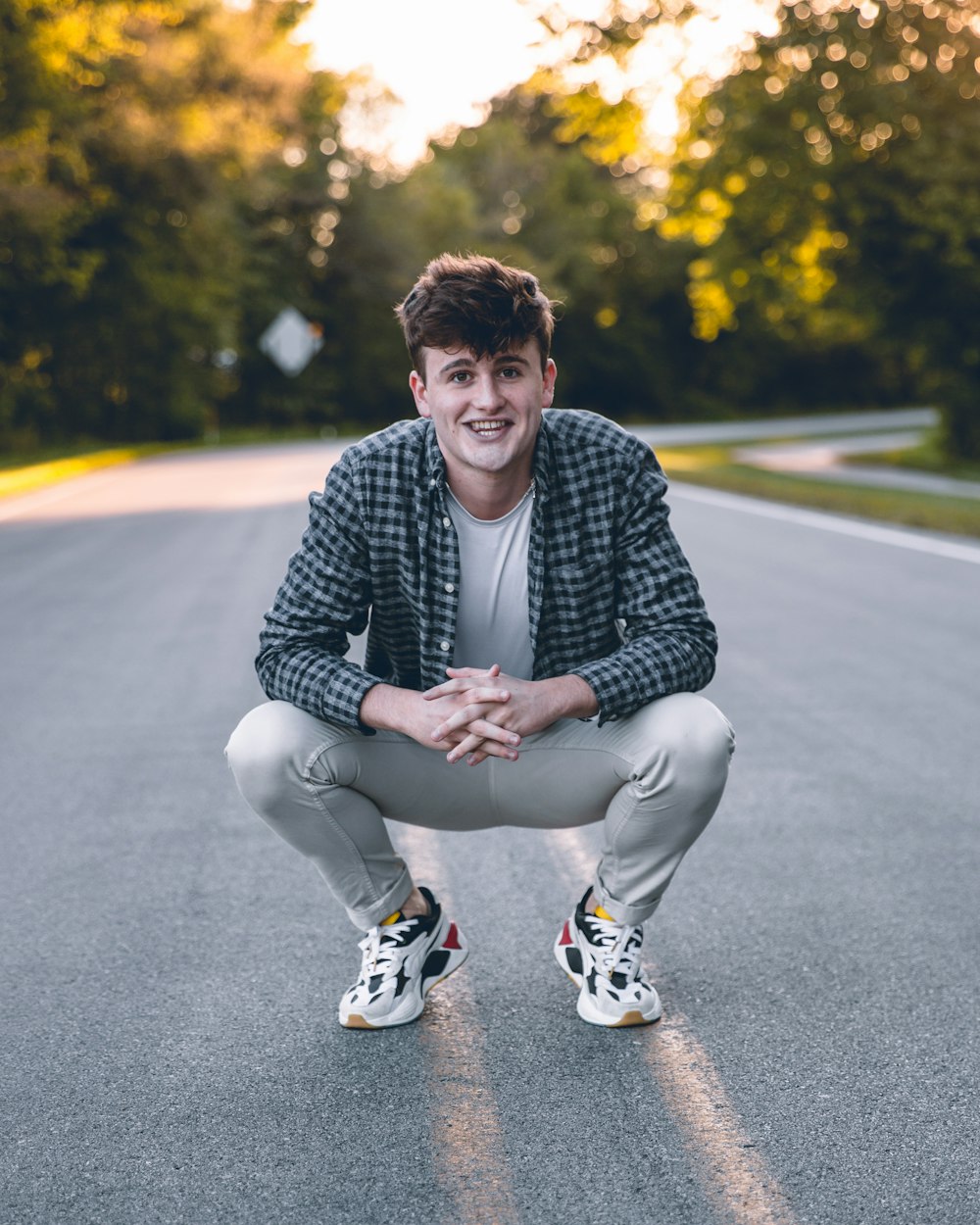 man in black and white checkered dress shirt sitting on gray asphalt road during daytime