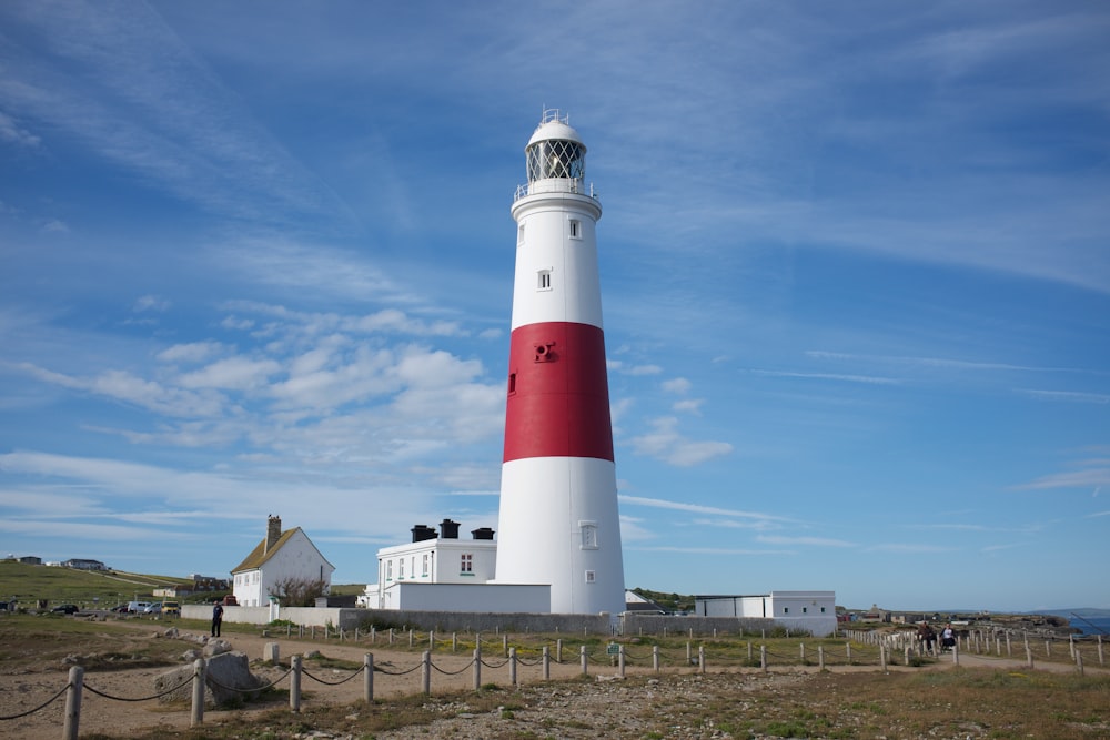 faro bianco e rosso sotto il cielo blu durante il giorno