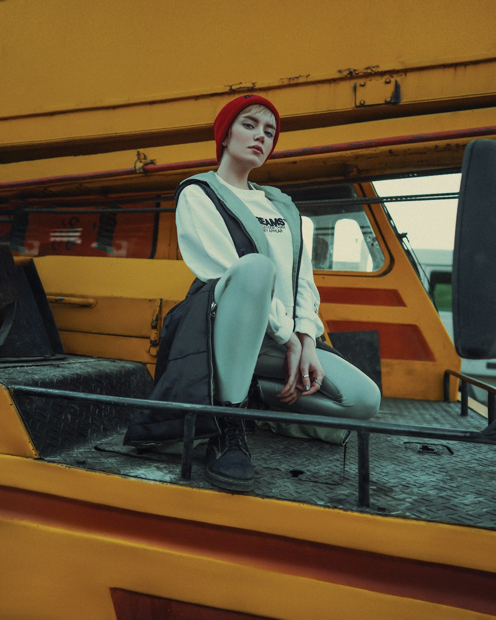 woman in white long sleeve shirt and black vest sitting on yellow and black metal frame