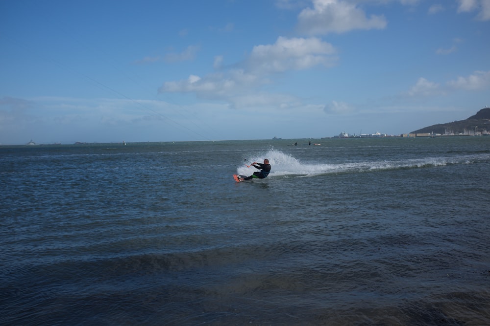person riding on white and red surfboard on sea during daytime