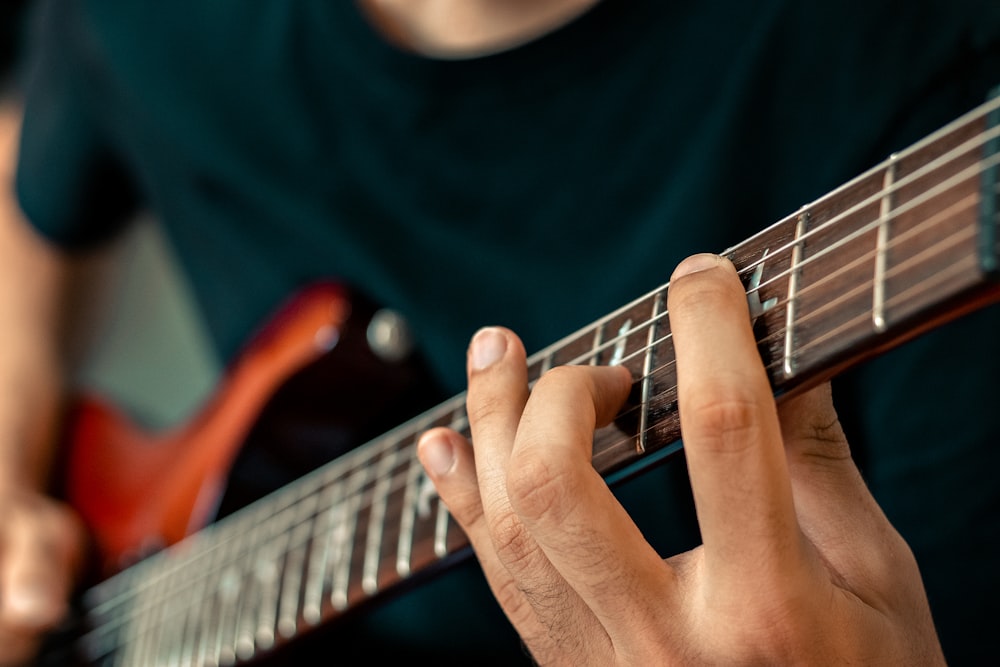 person playing guitar in close up photography