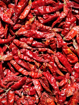 Close-up of vibrant dried chili peppers in wooden crates.