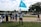 A group of people is gathered on a lawn with the United States Capitol building in the background. One person is holding a blue flag with a white crescent and star. Another person is holding a sign with a message about family and China. The scene appears to be a protest or demonstration.