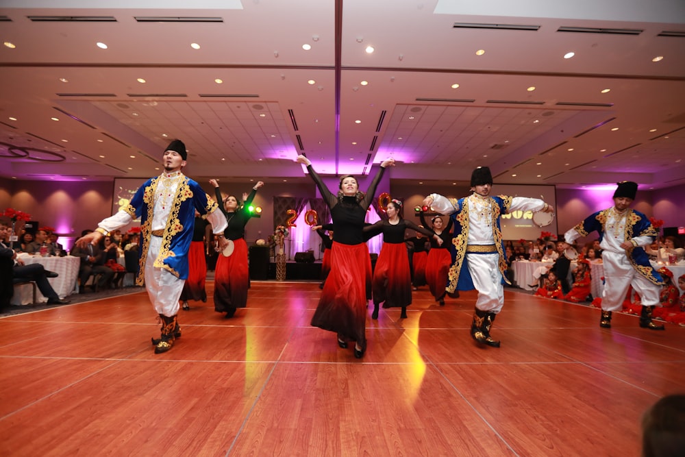 group of people in white and red traditional dress dancing on brown wooden floor