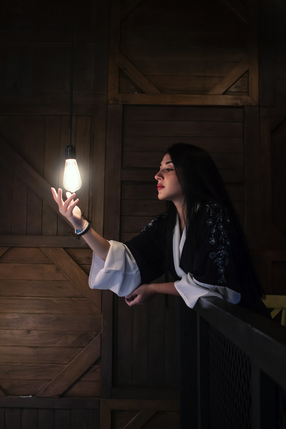 woman in black and white dress holding white light bulb