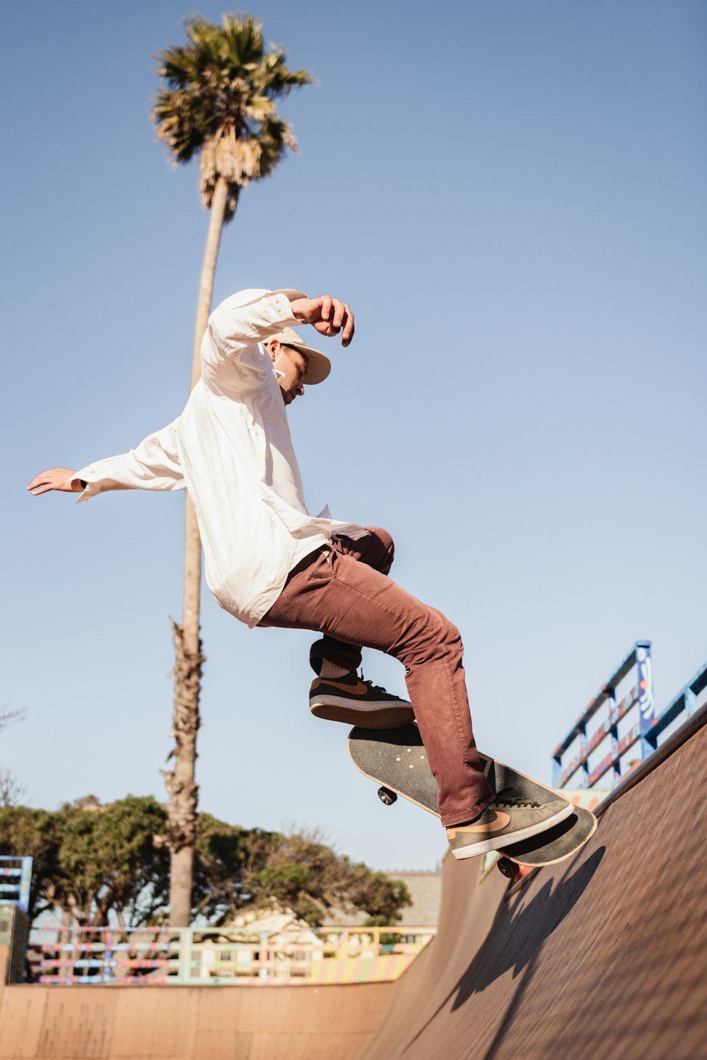 man in white t-shirt and blue denim jeans jumping on blue metal railings during daytime