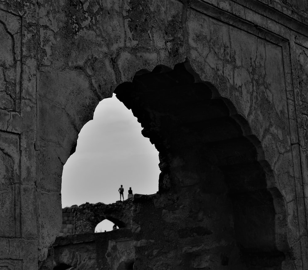 silhouette of people walking on arch shaped tunnel during daytime