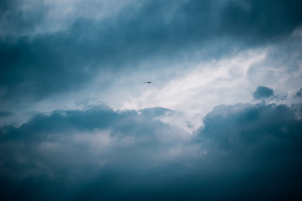 airplane flying under white clouds during daytime