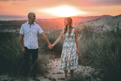 A warm, inviting photo of a couple holding hands during a sunset prayer moment.