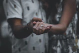 Couple holding hands with a blurred background of intimate wellness products.