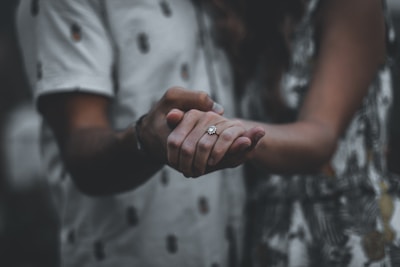 Softly lit photo of the couple holding hands, focused on their wedding rings.