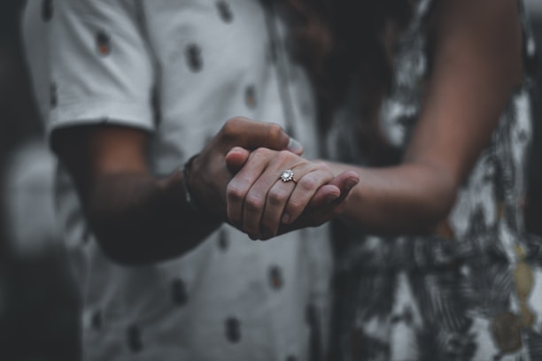 Happy couple holding hands, showing off their custom rings from yesmakers studio.