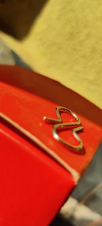 Close-up of a red heart detail embroidered on a black hoodie with blurred city lights in background.