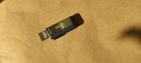A USB flash drive with a metal and plastic design, featuring a 128GB label. It rests on a textured brown surface with a visible shadow.