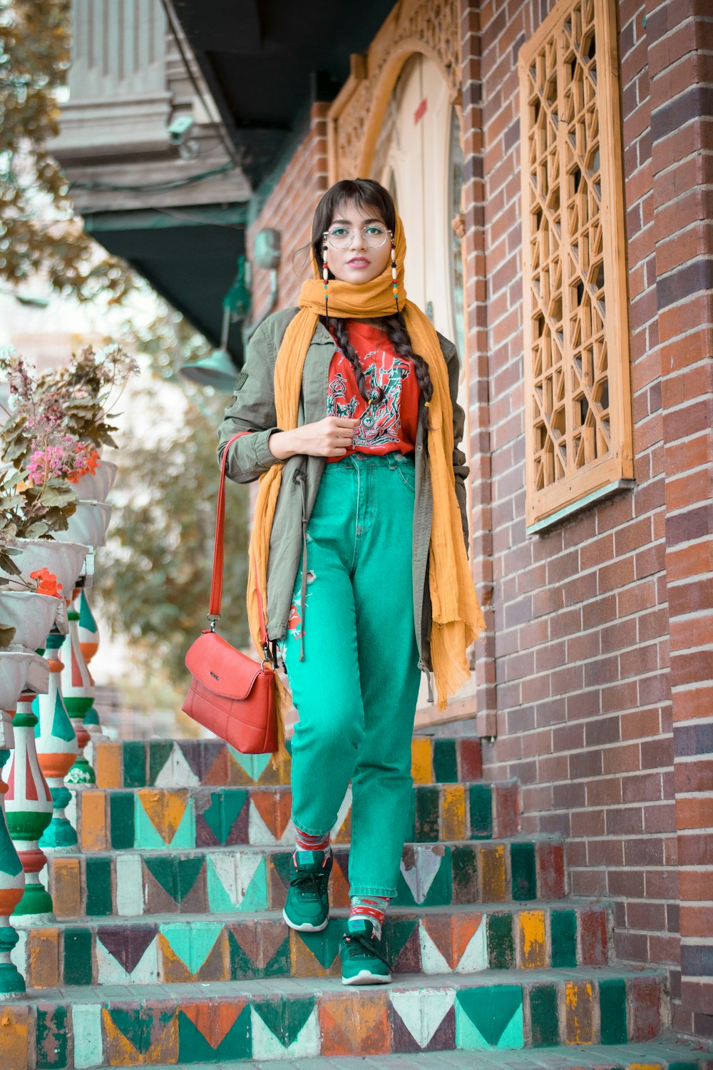 茶色のレンガの壁のそばに立つ緑と茶色のサリーを着た女性