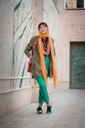 Model wearing a brightly colored layered outfit in a dynamic urban setting.