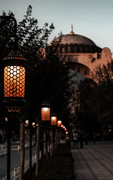 Elegant Moroccan lanterns casting soft light over a courtyard with palm trees at dusk