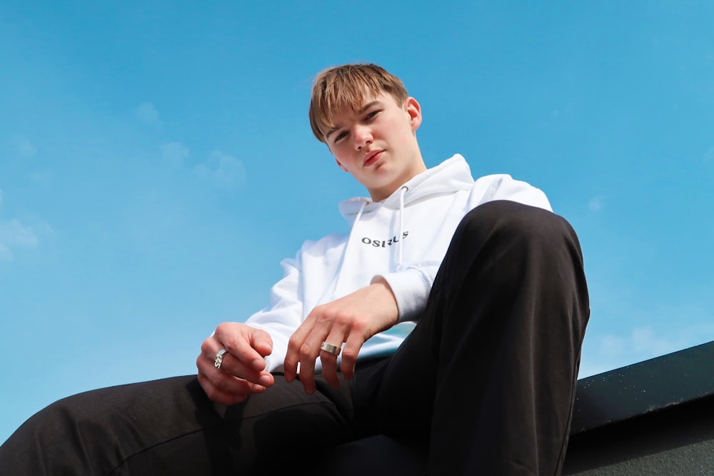 boy in white dress shirt and black pants sitting on black couch