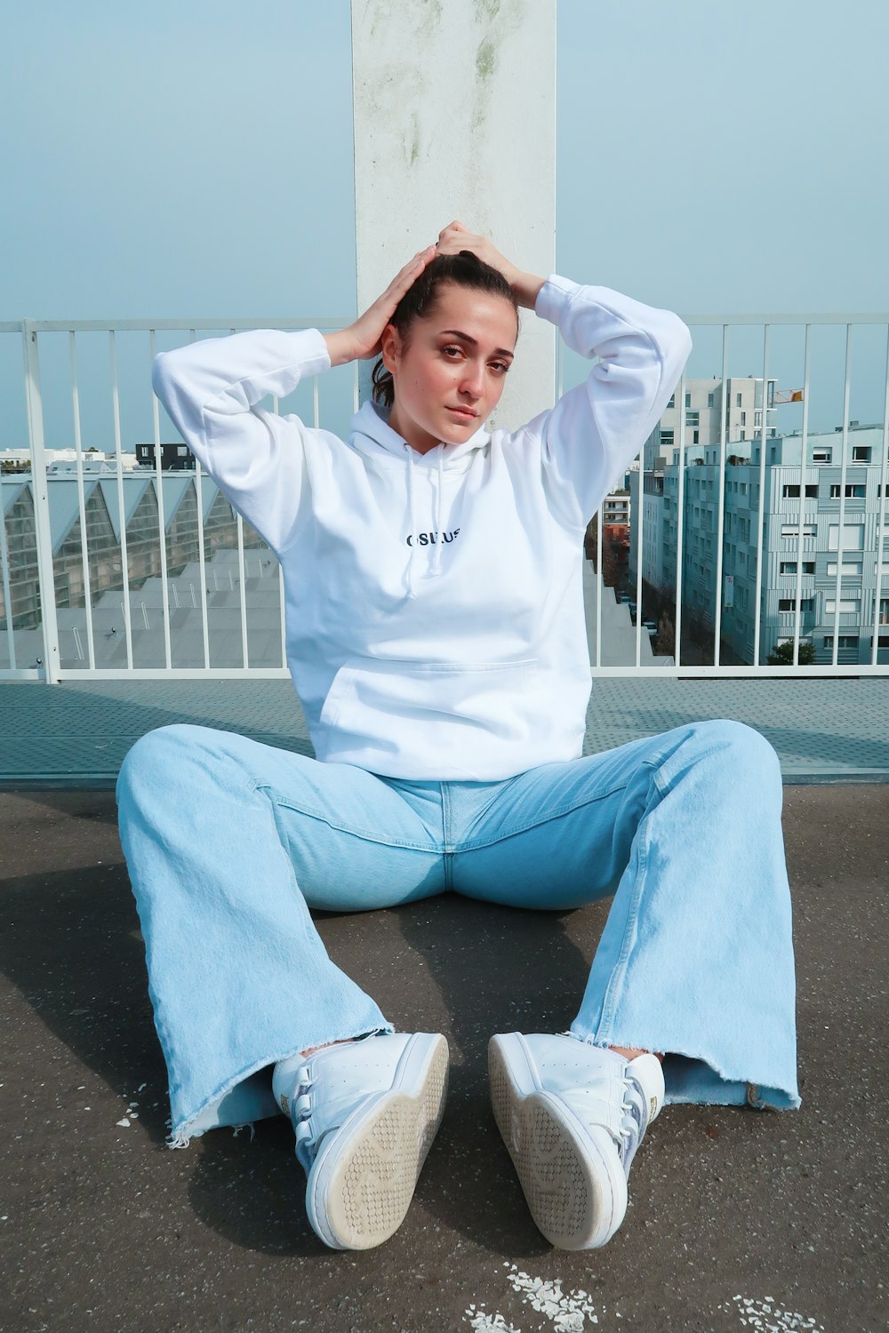 man in white hoodie and blue pants sitting on concrete bench