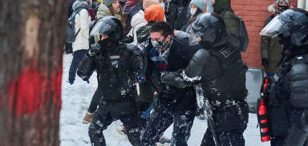 personnes en veste et casque noir et blanc sur un sol enneigé pendant la journée