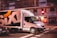 A white delivery truck with the word 'SIXT' displayed prominently on its side is driving through a city street. The environment suggests a motion blur effect, indicating speed and movement. Buildings and traffic lights are visible in the background.