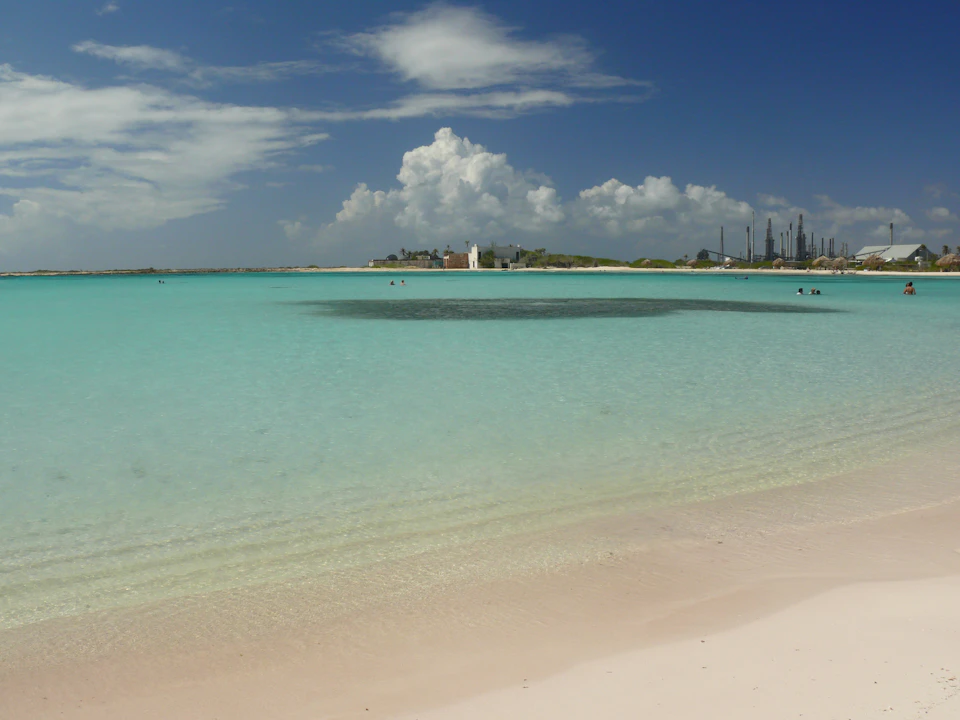 Serene beach scene with people enjoying day on sandy shoreline under clear blue sky