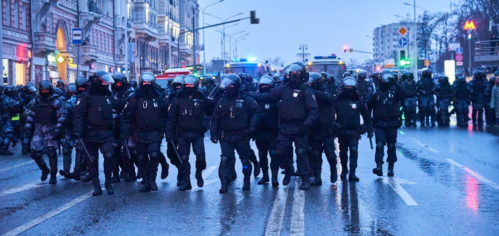 group of men in black and green uniform standing on road during daytime