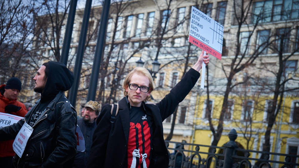 woman in black jacket holding white and blue signage