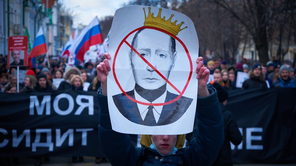 man in blue jacket holding white and red bird print banner