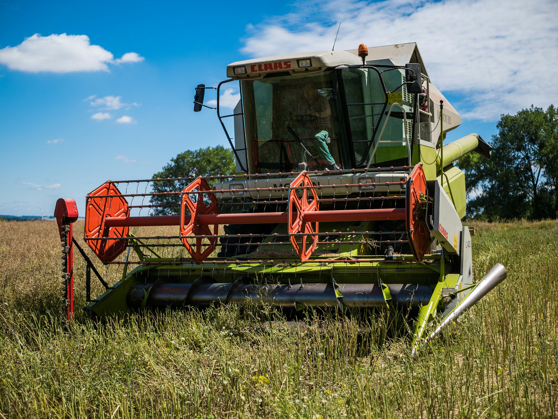 red and green heavy equipment on green grass field under blue sky during daytime