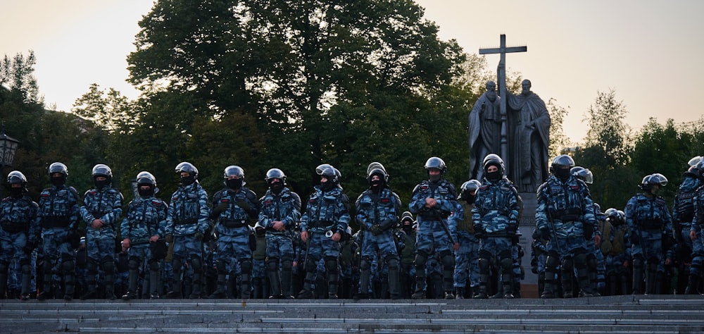 soldiers in black and gray camouflage uniform standing on gray concrete road during daytime