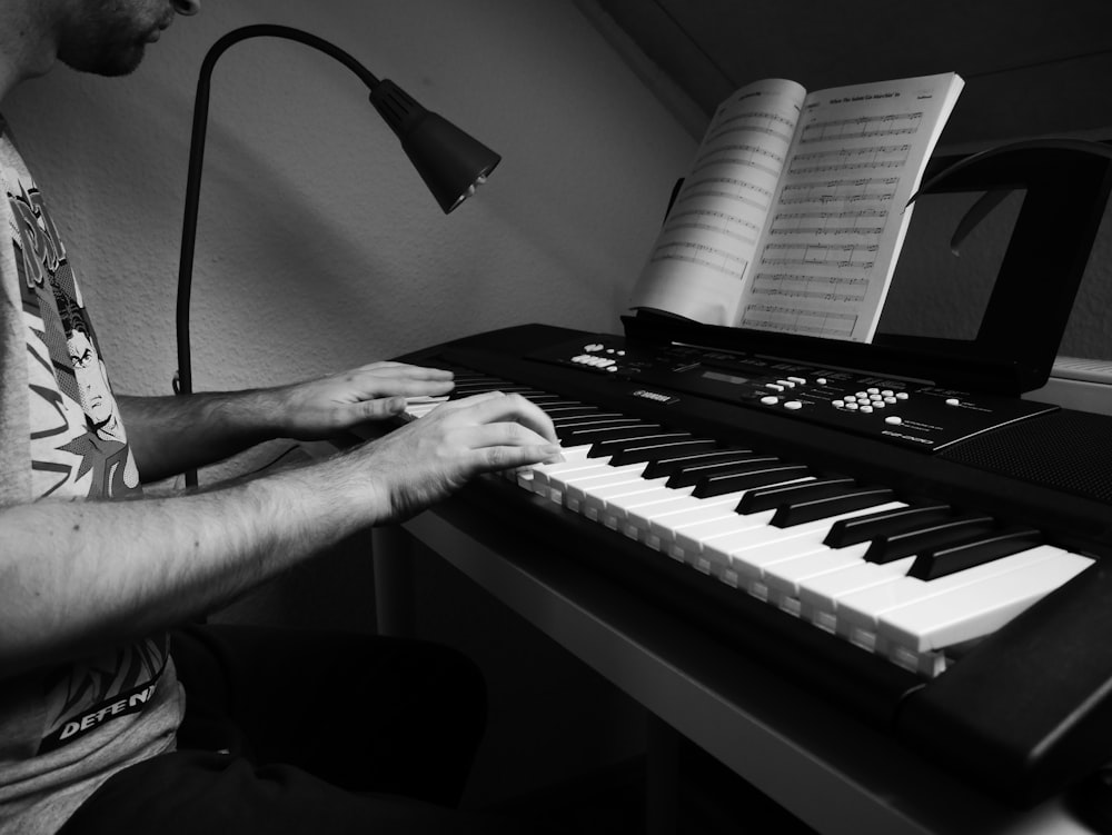 person playing piano in grayscale photography