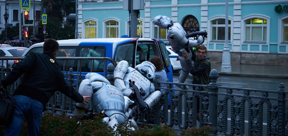 people in gray helmet riding on white and blue car during daytime