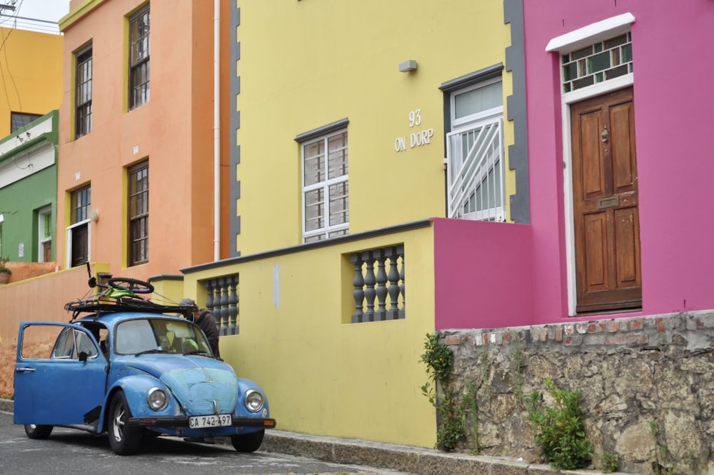 carro azul estacionado ao lado do edifício de concreto amarelo