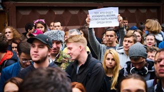 A diverse group of passionate people gathered in a bright banquet hall in Toronto, holding signs and sharing stories.