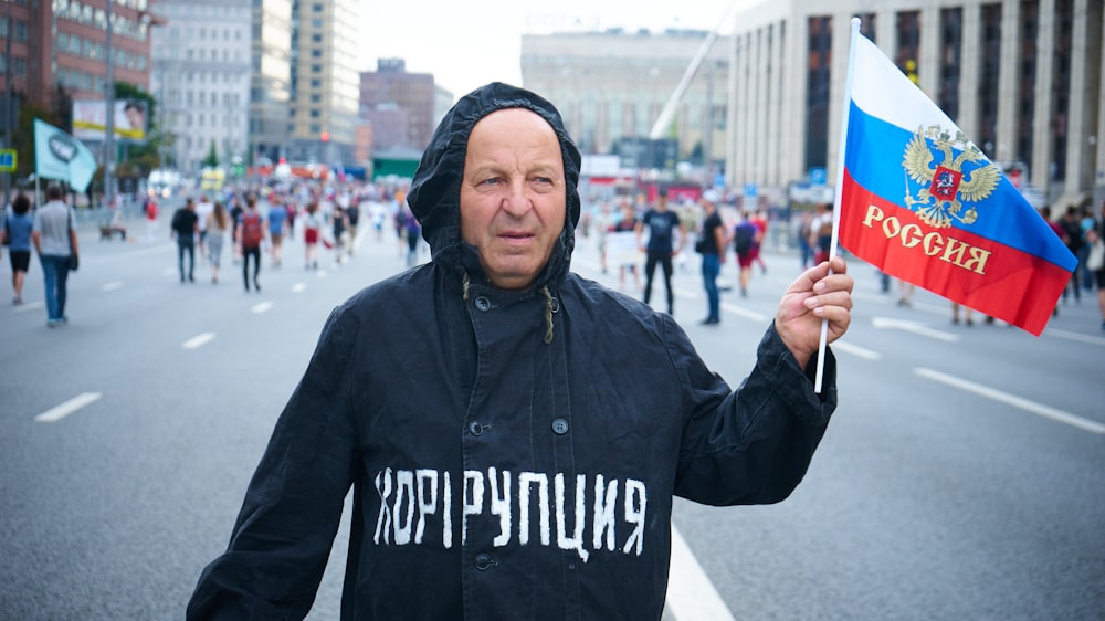 man in black and white hoodie holding orange and blue umbrella